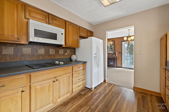 kitchen featuring dark countertops, tasteful backsplash, dark wood finished floors, white appliances, and a textured ceiling