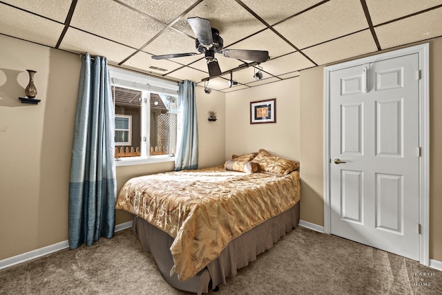 carpeted bedroom with a paneled ceiling and baseboards