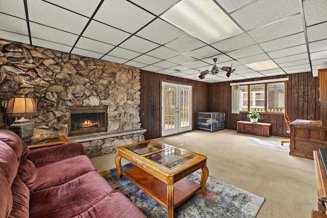 living area with wooden walls, a fireplace, french doors, a paneled ceiling, and carpet flooring