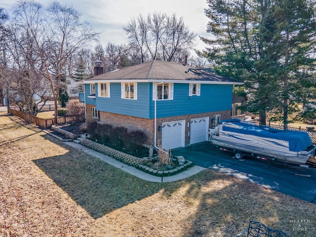 view of property exterior featuring fence, concrete driveway, an attached garage, brick siding, and a chimney