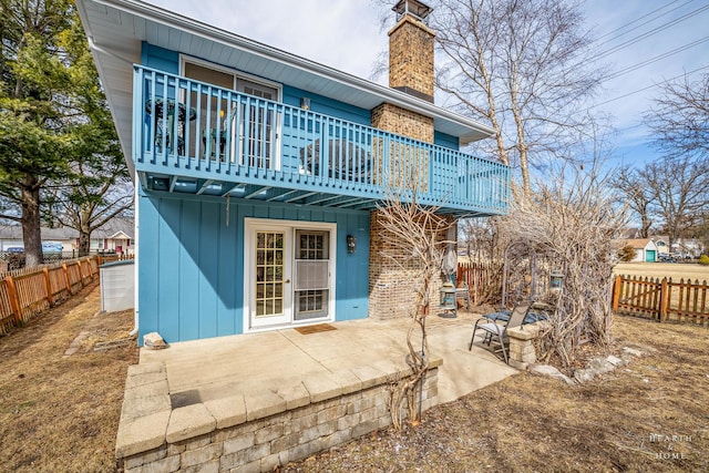 back of house featuring a patio area, a deck, a chimney, and a fenced backyard