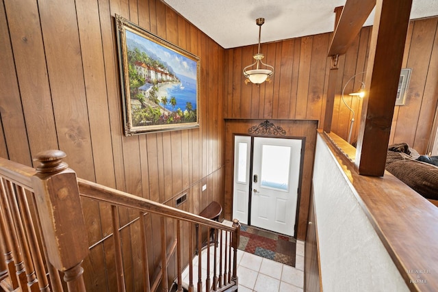 foyer entrance with light tile patterned floors, wooden walls, plenty of natural light, and visible vents