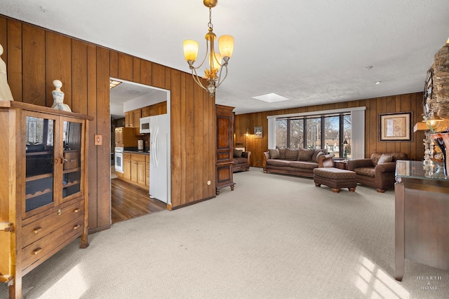 carpeted living area featuring a chandelier and wooden walls