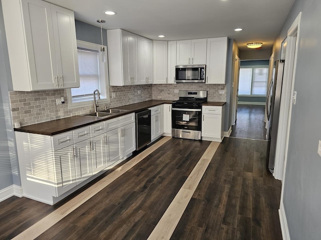 kitchen with a sink, stainless steel appliances, dark wood-style floors, and white cabinetry