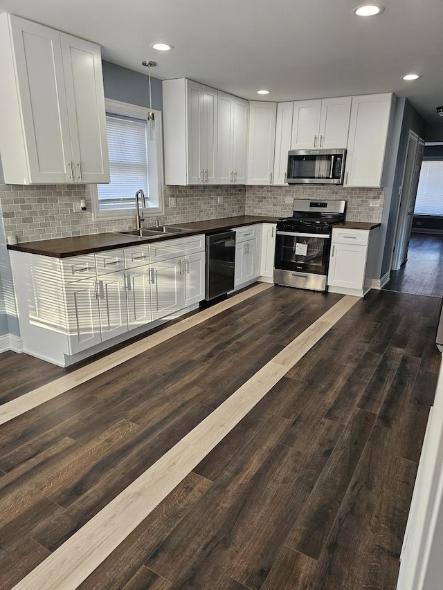 kitchen with dark countertops, appliances with stainless steel finishes, dark wood-type flooring, and a sink