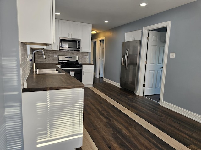 kitchen featuring a sink, stainless steel appliances, dark wood finished floors, and white cabinetry