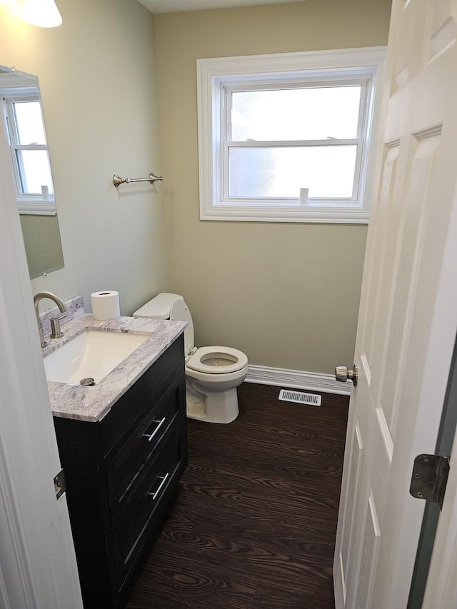 bathroom with visible vents, baseboards, toilet, wood finished floors, and vanity