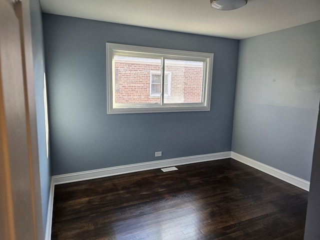 unfurnished room with baseboards and dark wood-type flooring