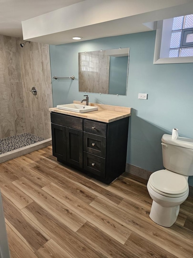 bathroom featuring vanity, toilet, wood finished floors, and tiled shower