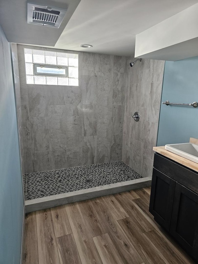 bathroom featuring visible vents, tiled shower, vanity, and wood finished floors