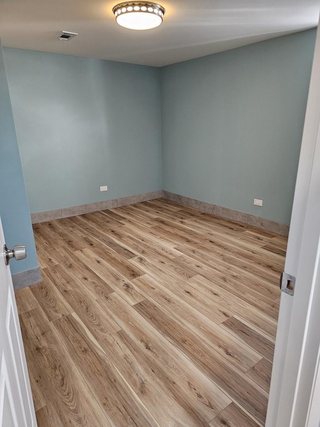 unfurnished room featuring visible vents, baseboards, and wood finished floors