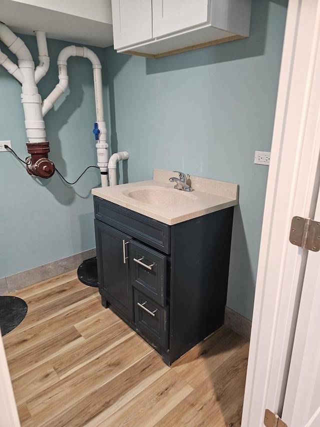 bathroom with vanity, wood finished floors, and baseboards