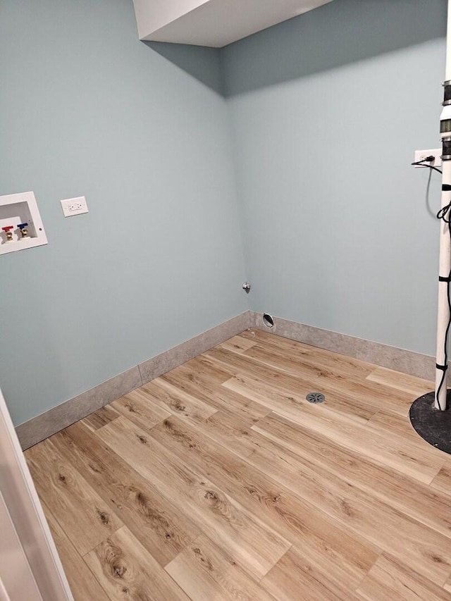 clothes washing area featuring baseboards, washer hookup, wood finished floors, and laundry area