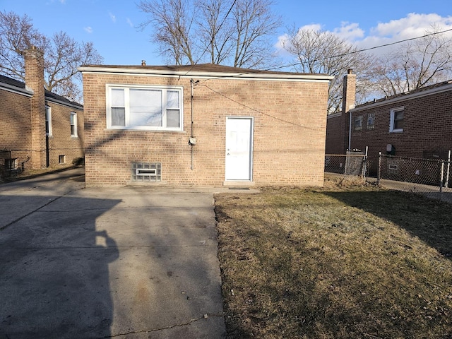 rear view of property featuring brick siding, a lawn, and fence