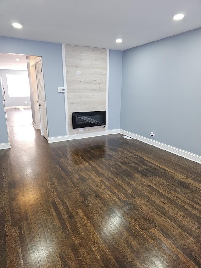 unfurnished living room with hardwood / wood-style flooring, recessed lighting, a fireplace, and baseboards