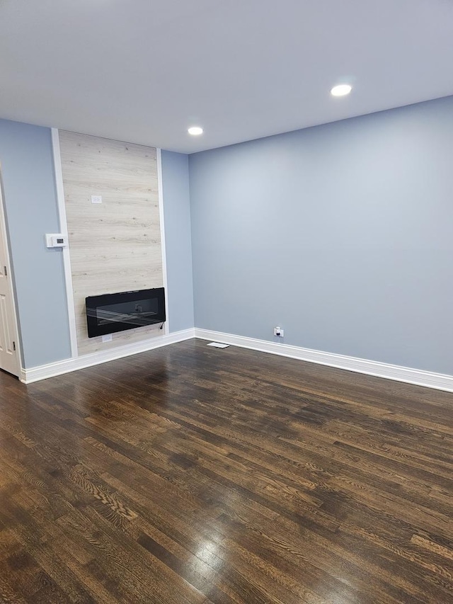 unfurnished living room with recessed lighting, baseboards, and dark wood finished floors