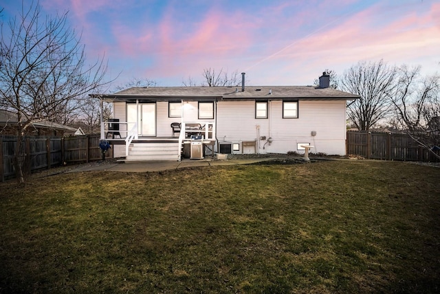 back of house featuring a fenced backyard, a lawn, a chimney, and a patio