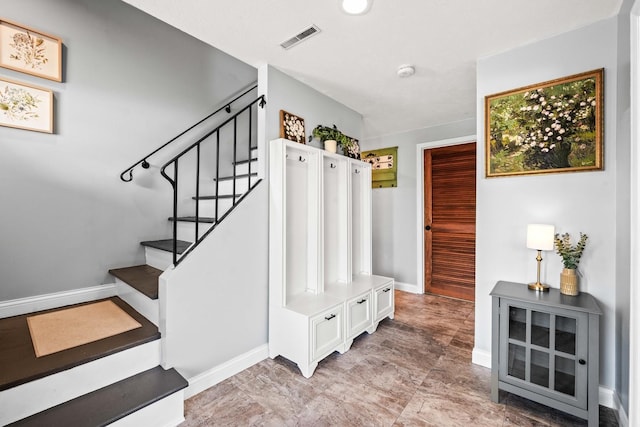 staircase featuring baseboards and visible vents