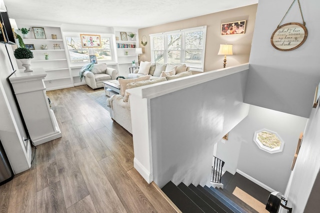 living room featuring a textured ceiling, baseboards, and wood finished floors