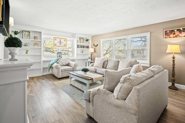 living room with baseboards, a textured ceiling, and wood finished floors