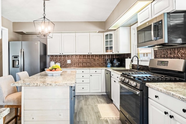 kitchen featuring a sink, stainless steel appliances, white cabinetry, a kitchen breakfast bar, and backsplash