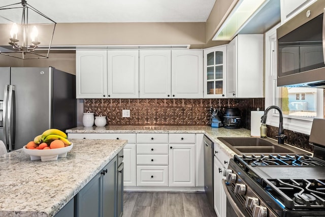 kitchen with light wood-type flooring, backsplash, appliances with stainless steel finishes, and white cabinetry