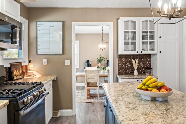 kitchen with gas range, stainless steel microwave, a notable chandelier, and wood finished floors