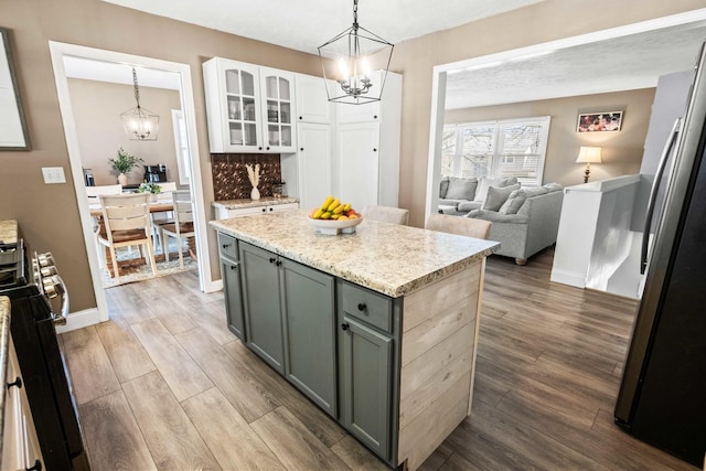 kitchen with freestanding refrigerator, an inviting chandelier, and wood finished floors