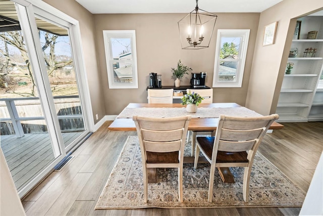 dining room with light wood-type flooring, a healthy amount of sunlight, and visible vents