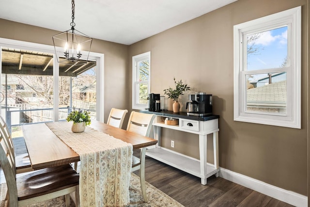 dining area featuring an inviting chandelier, dark wood-type flooring, and baseboards