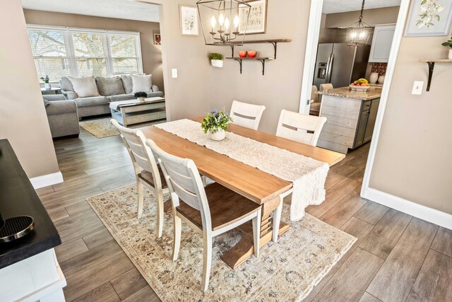 dining area featuring baseboards, wood finished floors, and a chandelier