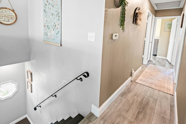 stairway featuring wood finished floors, visible vents, and baseboards