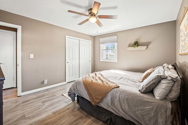 bedroom with a closet, a ceiling fan, baseboards, and wood finished floors