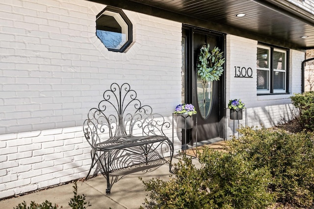 view of exterior entry with covered porch and brick siding