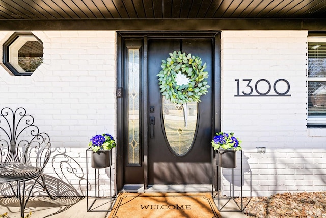 property entrance featuring a porch and brick siding