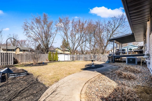 view of yard with an outbuilding, central air condition unit, a shed, and a fenced backyard