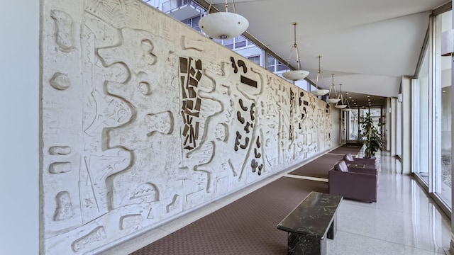 hallway with plenty of natural light, speckled floor, and high vaulted ceiling