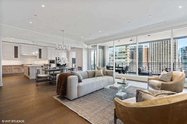 living room with an inviting chandelier, dark wood-style flooring, a wealth of natural light, and ornamental molding