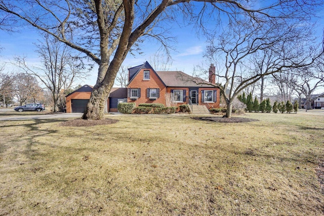 view of front of house featuring brick siding, a chimney, a detached garage, and a front lawn