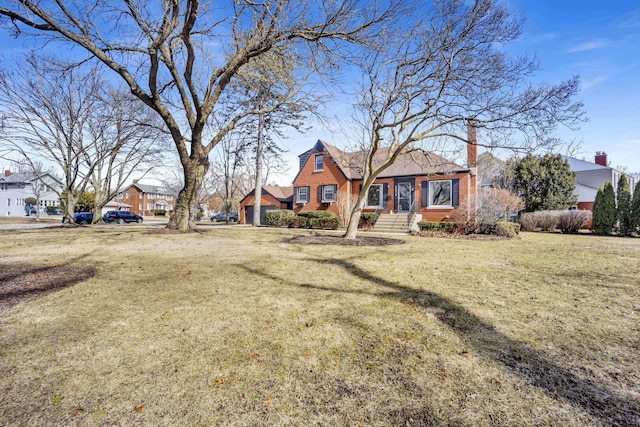 view of front facade with a front yard, brick siding, and a chimney