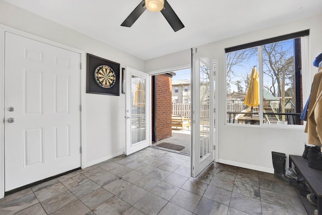 doorway to outside featuring baseboards and a ceiling fan