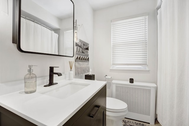 bathroom featuring toilet, radiator, and vanity