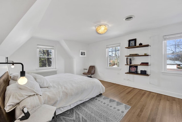 bedroom featuring visible vents, multiple windows, baseboards, and wood finished floors