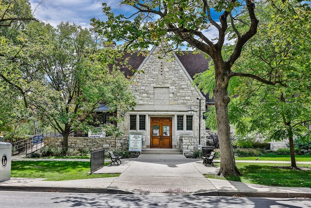 view of front of house featuring french doors, stone siding, a front lawn, and fence