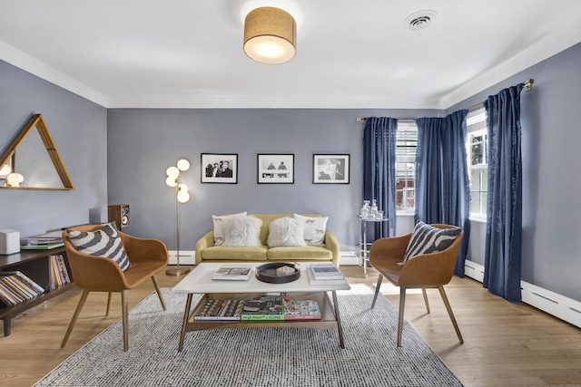 living area featuring visible vents, a baseboard radiator, and wood finished floors