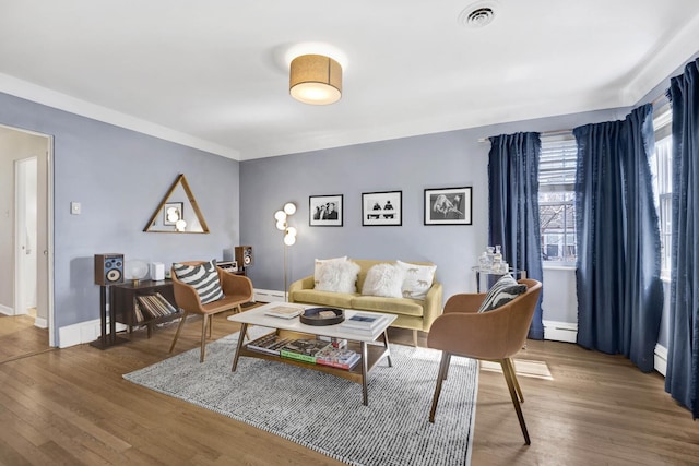 living area featuring visible vents, baseboards, baseboard heating, and wood finished floors