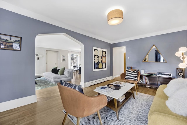 living area with arched walkways, baseboard heating, baseboards, and wood finished floors