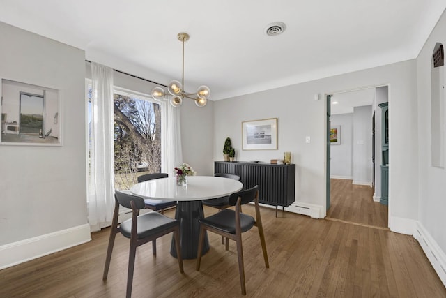 dining area with visible vents, a baseboard heating unit, baseboards, and wood finished floors