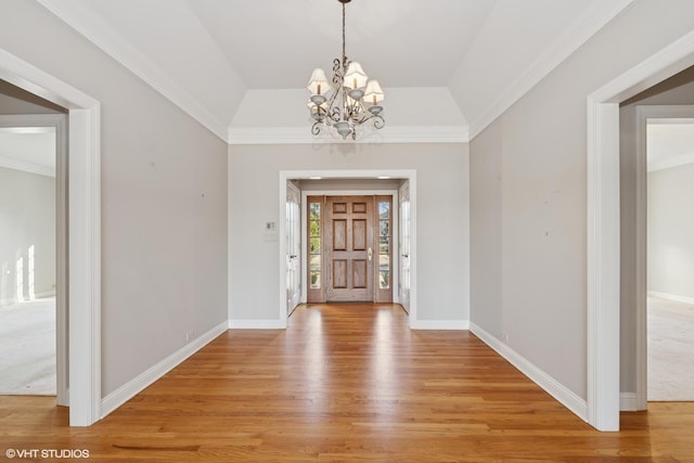 foyer entrance with lofted ceiling, light wood-style floors, baseboards, and a chandelier