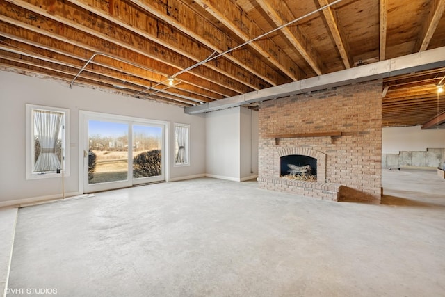 unfurnished living room featuring a brick fireplace and concrete floors